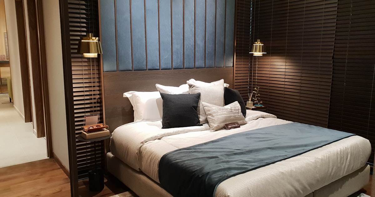 A dark paneled bedroom seen from the foot of the bed, looking along its length