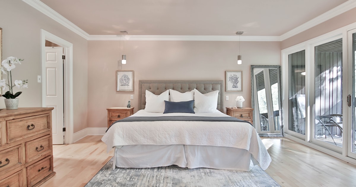 A compact bedroom with a wooden chest of drawers beside the bed and doors on two walls