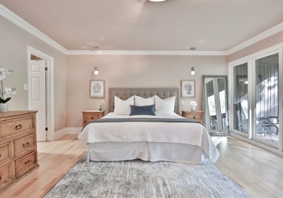 A compact bedroom with a wooden chest of drawers beside the bed and doors on two walls