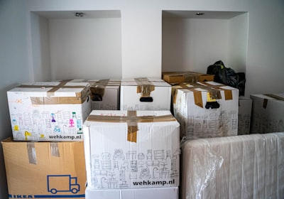 Stacked cardboard moving boxes wrapped in plastic, filling a bare room