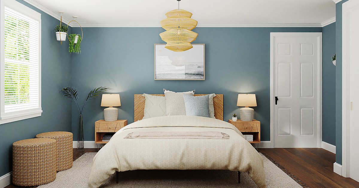 A blue walled bedroom with a wooden bed, a bedside lamp on each side and a pendant light overhead