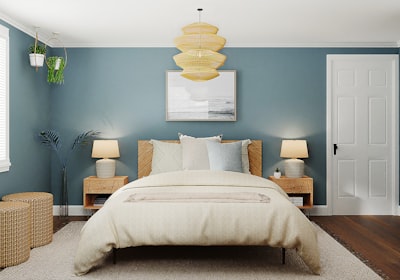 A blue walled bedroom with a wooden bed, a bedside lamp on each side and a pendant light overhead