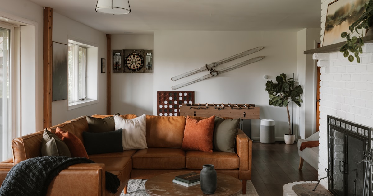 A living room with a brown leather sofa, a fireplace and decorative objects on the wall