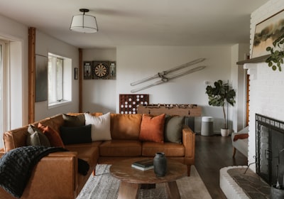 A living room with a brown leather sofa, a fireplace and decorative objects on the wall
